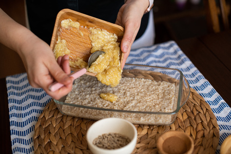 chef at work, making baked oatmeal with banana, blueberries, walnut and raisins. preparing food to bake. concept for cooking.の写真素材