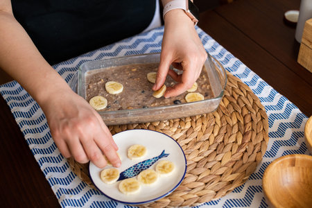 chef at work, making baked oatmeal with banana, blueberries, walnut and raisins. preparing food to bake. concept for cooking.の写真素材