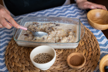 chef at work, making baked oatmeal with banana, blueberries, walnut and raisins. preparing food to bake. concept for cooking.の写真素材