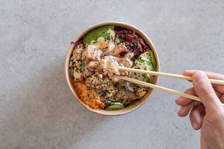 California Poke Bowl with salmon, avocado,  crab surimi, carrot, red cabbage, ginger, sushi rice and cucumber. Delicious hawaiian poke bowlの写真素材