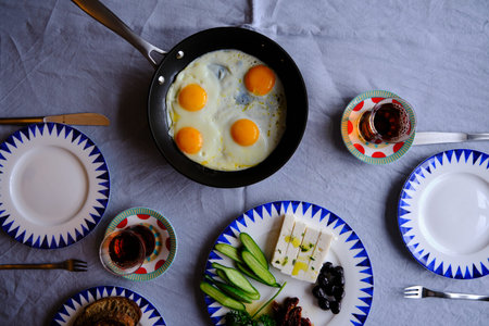 Traditional Turkish Breakfast with Sunny Side Up Eggs, Feta Cheese, Tea, Olives and Cucumber....