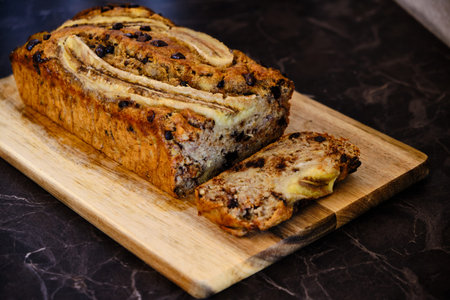 Homemade healthy banana bread served on a wooden board, black marble surface