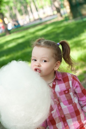 girl eating cotton candy in the park の写真素材