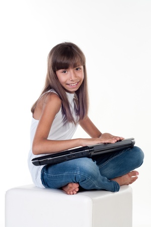 Cute little girl is sitting with laptop, isolated over whiteの写真素材