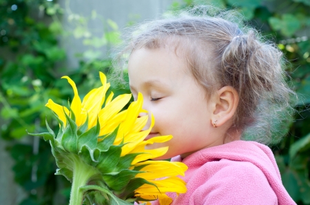 Beautiful little girl and sunflower, outdoor portraitの写真素材