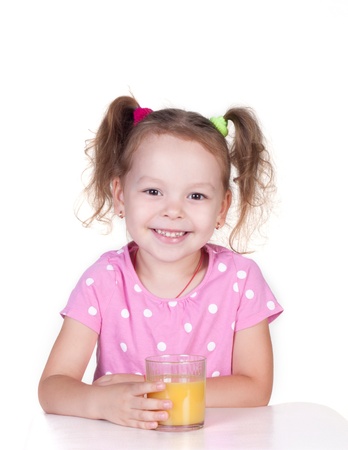 Cute little girl is drinking orange juice, isolated over whiteの写真素材
