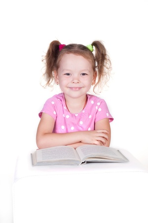 Cute little girl is reading a book, isolated over whiteの写真素材