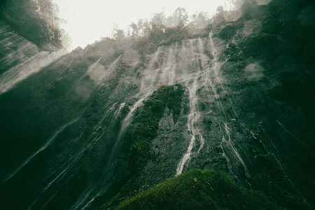 Beautiful waterfall in the forest with fog and sunlight. Toned.の写真素材