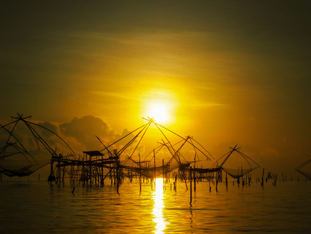 silhouette Thai traddition lift fishing equipment in  morning light  at Pakpra, Patthalung province, Thailand, with little cumulus cloud on sky. The equipment still using by let it down into water wait untill fish come the lift it up into the air.の写真素材