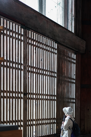 elder woman look out the wooden windowの写真素材