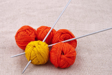 Bright balls of yarn with knitting needles on the canvas fabric