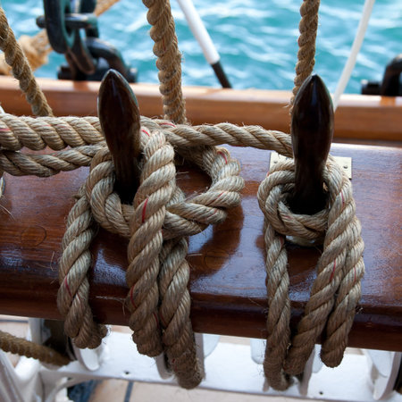 Two ropes control the sails, tied to a wooden beam