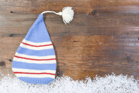 Wooden background with cap, snow on the border and copyspace for your Christmas text