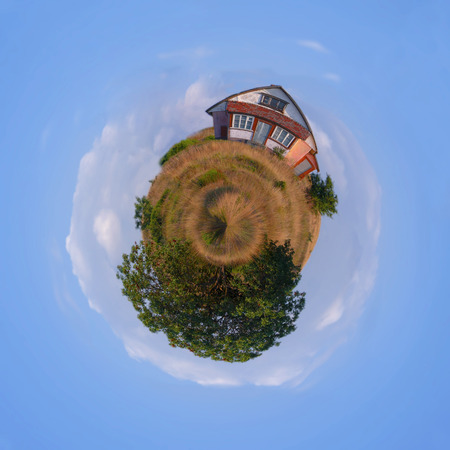 Your own Planet Earth: spherical panorama of a meadow with a little house and green trees against blue cloudy skyの写真素材