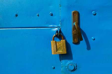 Blue metal door with a old brass padlock.の写真素材