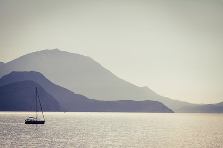 Small boat against the blue misty mountains. Adriatic sea, Montenegro. Tinted and coloured photo.の写真素材