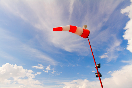 Turned by the wind red and white windsock against blue skyの写真素材