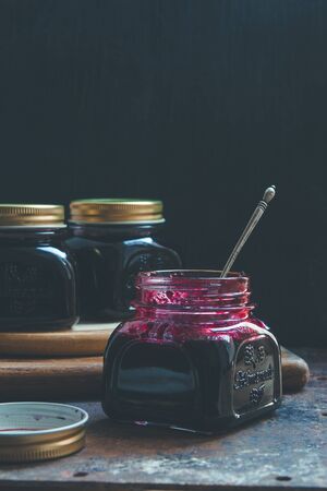 Opened jam-jars on a table with a silver teaspoon sanked in jamの写真素材