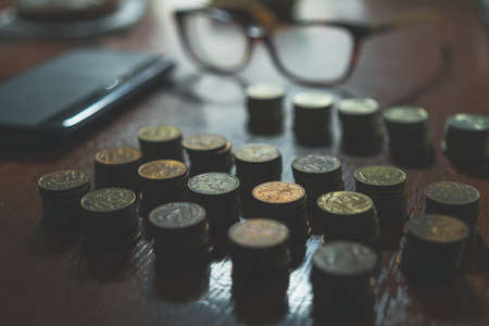 Row of coins and eyeglasses laying on a table, poverty conceptの写真素材