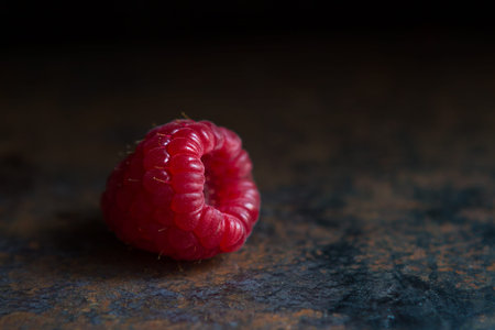 One raspberry on a rough metal rusty surface, wallpaper