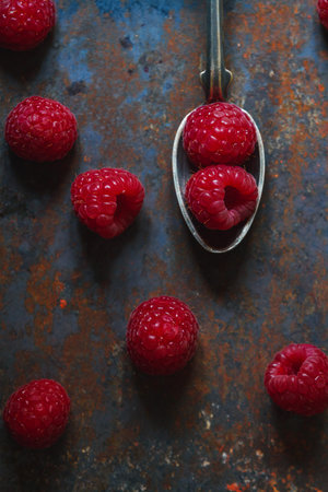 Fresh garden raspberries in a spoon on the table, food background