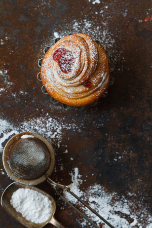 Cruffin bun with raspberry filling on a dark table, top view