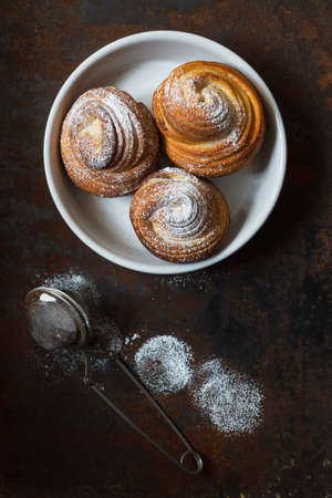Jast baked cruffins covered by sugar powder on a white plate, food backgroundの写真素材