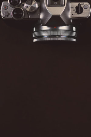 Dark brown background with digital camera, top view with a copy space