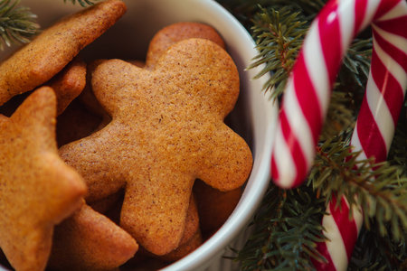 Christmas gingerbread men and stars, cookies in a white bowl, and a candy cane close up
