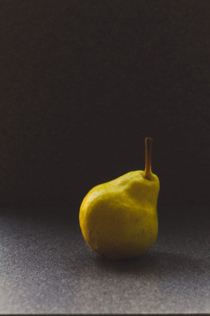 Yellow ripe uneven pear on a gray background, fruit posterの写真素材