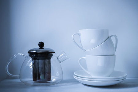 Several white cups for tea on a table with milk and a jar, toned