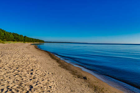 Sandy Beach with Calm Water Against Blue Skiesの写真素材