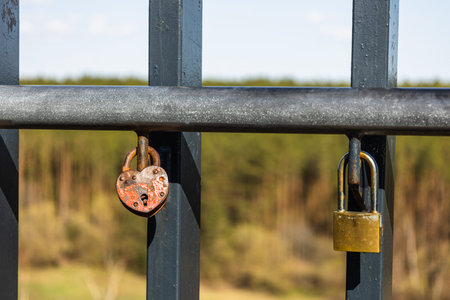 Closeup view of heart-shaped love padlock hanging on a bridge fence.