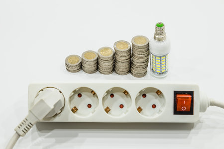 Stack of ascending Euro coins with a light bulb and outlet extension socket. Energy saving concept.の写真素材
