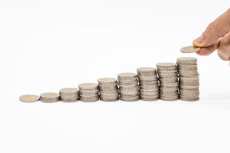 Hand placing coin on stacks. Wealth, success, finance, money growth and saving money concept.の写真素材