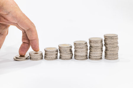 Fingers step on piles of coins in ascending order. Business and financial growth concept.の写真素材