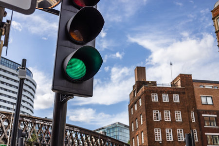 Green Traffic Light Signal in an Urban Cityscape with Modern and Historic Buildingsの写真素材