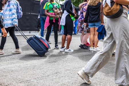 Busy urban scene with people walking and rolling suitcases on a city streetの写真素材