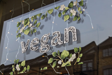 Vegan window display with leafy design and string lights in city storefront