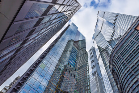 Tall Reflective Office Towers with Glass Facades Captured from Street Level Looking Up