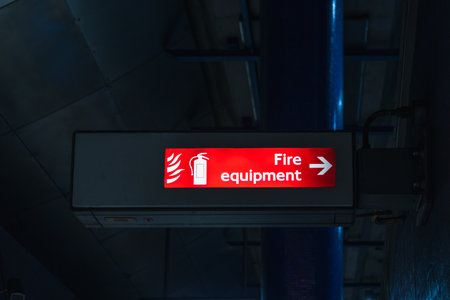Illuminated Fire Equipment Sign with Arrow in Dark Indoor Industrial Settingの写真素材
