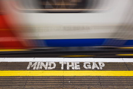 Blurry London Underground Train Passes MIND THE GAP Warning on Platform Edge, UK Transit Safetyの写真素材
