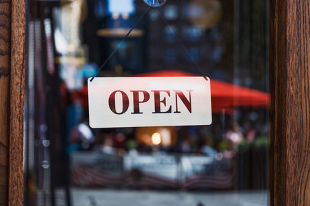 Open Sign on Storefront Glass with Blurred City Street and Outdoor Cafe Reflections