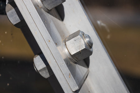 Close up of stainless steel bolt and nut securing angled beam plate in industrial structure
