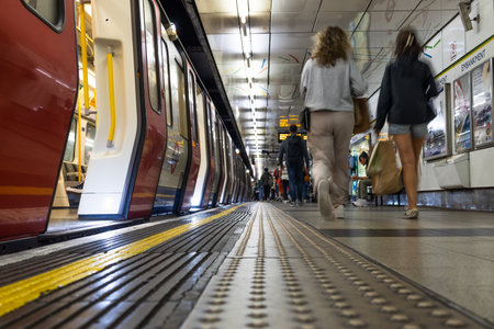 London Tube train at underground station platform as commuters walk past