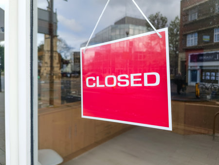 Red Closed sign hanging on glass door of empty shopfrontの写真素材