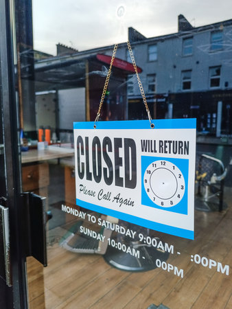 Closed sign on cafe door with empty seating inside and city reflectionsの写真素材