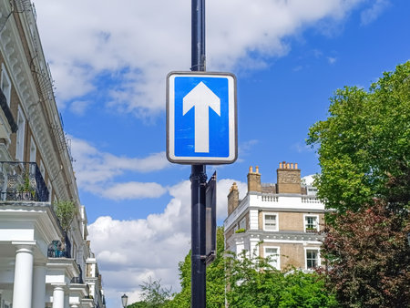 One Way Traffic Sign on UK Residential Street with Blue Arrow and Urban Road Safetyの写真素材
