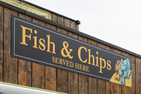 Fish and chips sign on a rustic wooden food stall exterior. Wareham, UK, 3 July 2024のeditorial素材