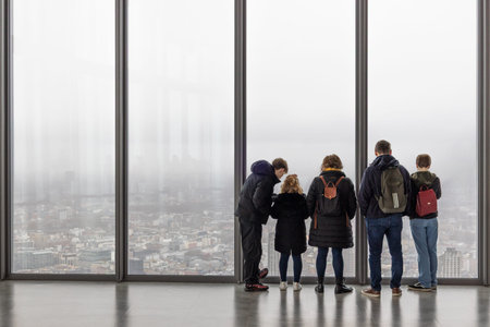 People looking at foggy London city view from a high window. London, UK, 10 December 2023